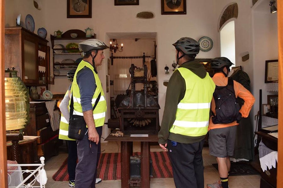tourists cyclists inside Aristaios' folklore museum, looking at the old traditional utensils and furniture
